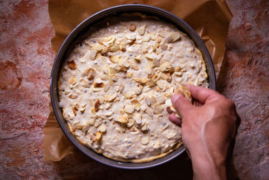 Geröstete, gehobelte Mandeln werden auf einer Quiche verteilt.