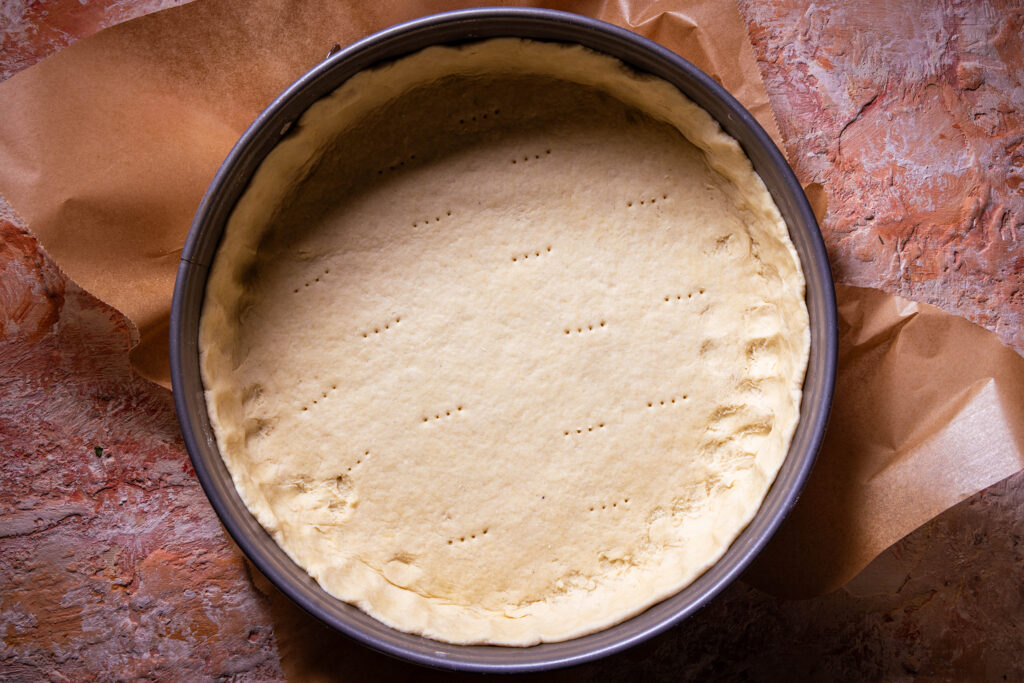 Eine Springform ausgelegt mit veganem Quark-Öl-Teig.