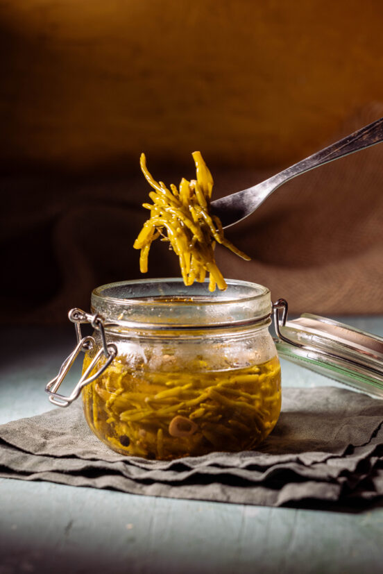 Salicorne Pickles - eingelegter Meerspargel - in einem Glas, eine Gabel holt eine Portion heraus.