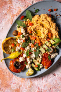 Veganer Scharfer Schafskäse Dip - Hot Sheperd - mit verschiedenen Beilagen auf einem Teller angerichtet.