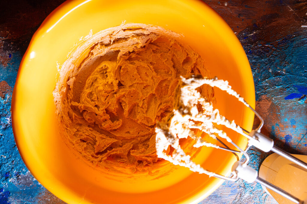 Waffelteig wird in einer orangen Teigschüssel gemixt.