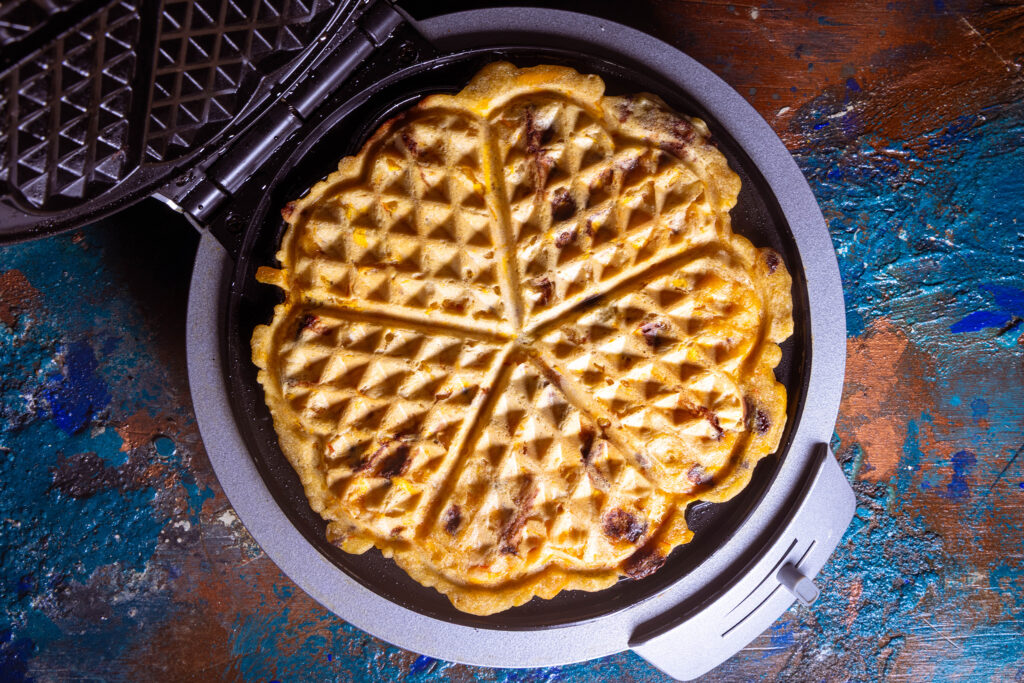Eine herbstliche Waffel mit Kürbis und Schokolade wird im Waffeleisen gebacken.
