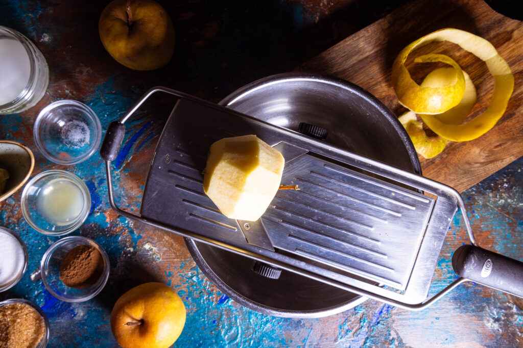 Ein geschäler Apfel wird auf einer Mandoline gehobelt.