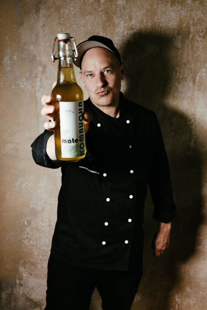 Sean Moxie hält eine Flasche selbstgemachten Mate-Kombucha