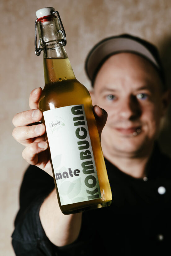 Sean Moxie hält eine Flasche selbstgemachten Mate-Kombucha