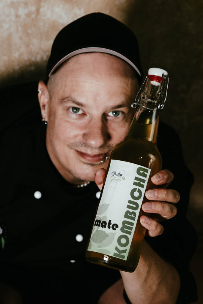 Sean Moxie hält eine Flasche selbstgemachten Mate-Kombucha