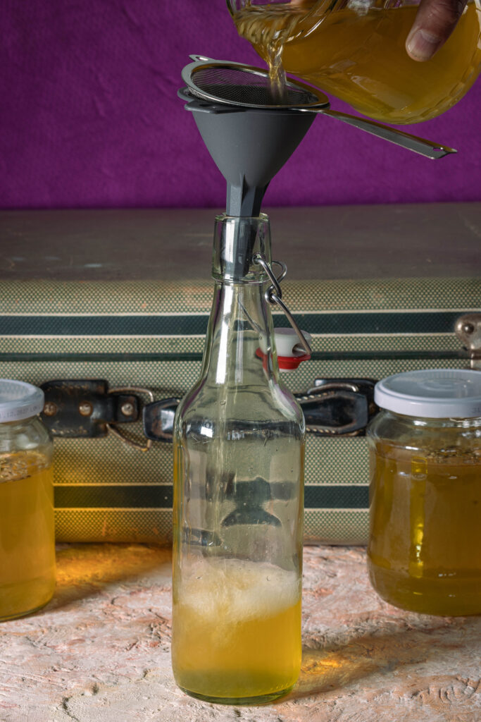 Mate Kombucha wird in eine Flasche abgeseiht.