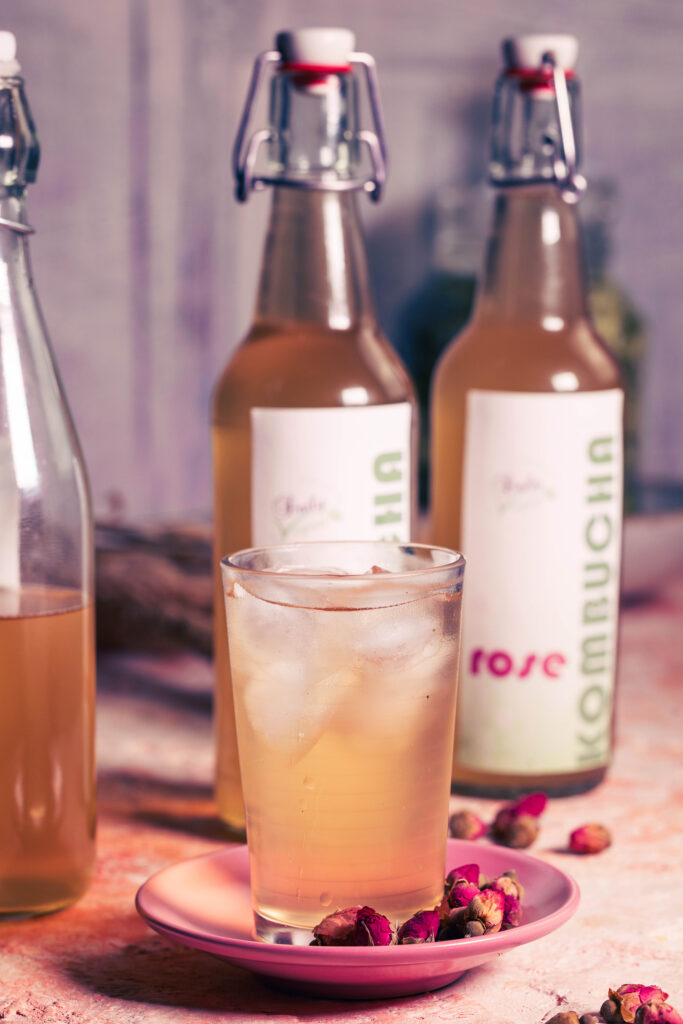 Rosen-Kombucha - in einem Glas mit Eiswürfeln und abgefüllt in Flaschen.