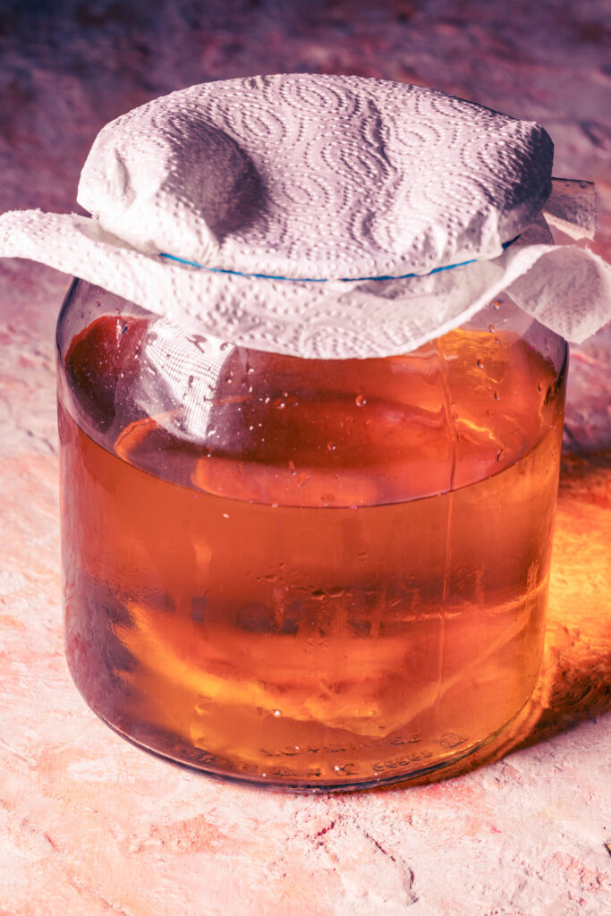 Kombucha fermentiert in einem großen Glasgefäß.