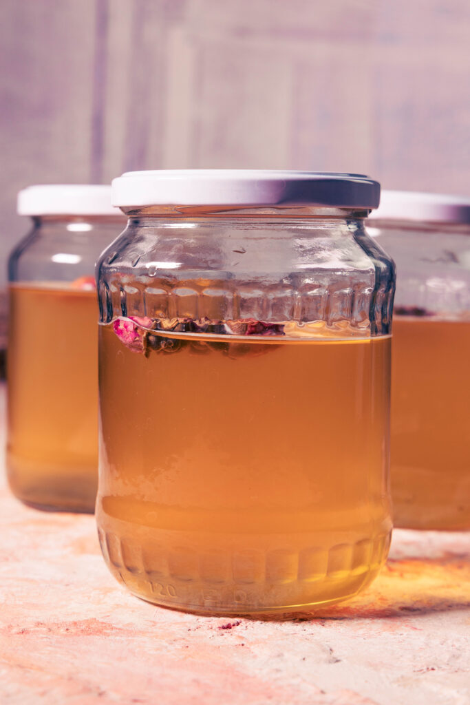 Rosen-Kombucha-Zweitfermentation in mehreren verschlossenen Scharubgläsern.