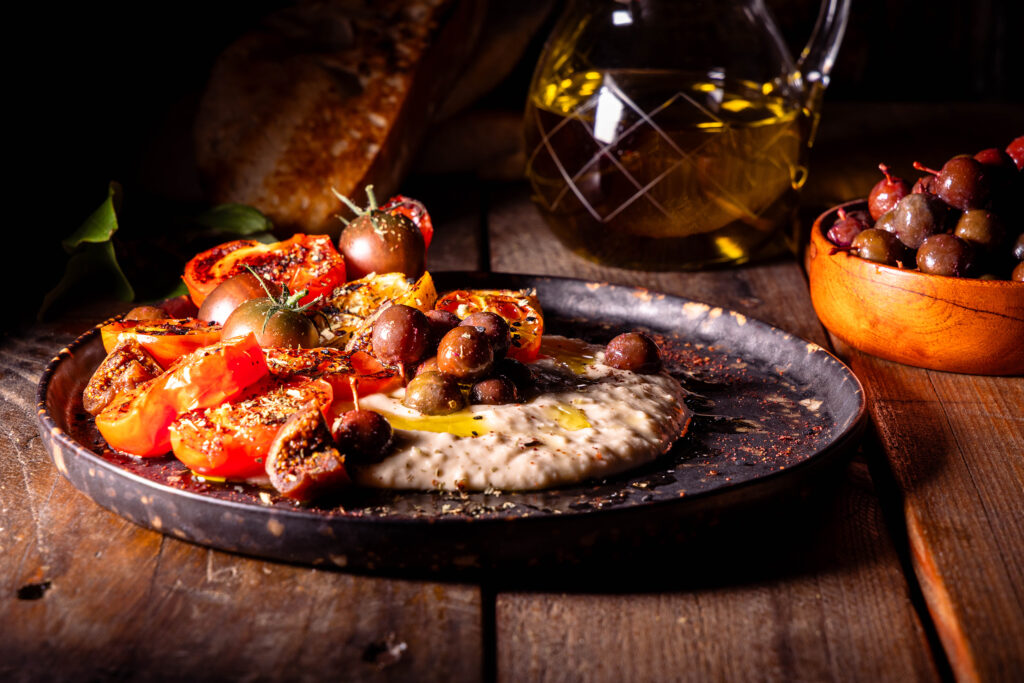 Heimische und regionale „falsche Oliven“, selbstgemacht aus unreifen Schlehen. Hier mit gegrillten Tomaten auf Bohnenhummus.