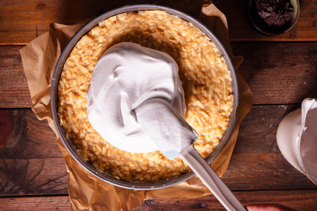 Vegane Zimtsahne wird auf der Apfeltorte verteilt.