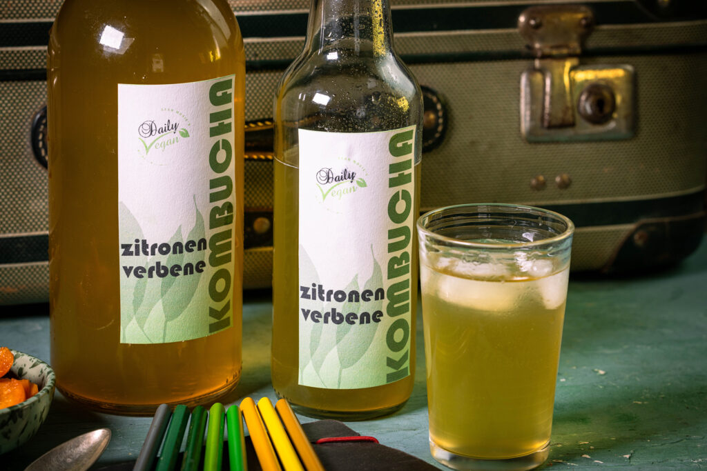 Zitronenverbene-Kombucha in einem Glas und in Flaschen.