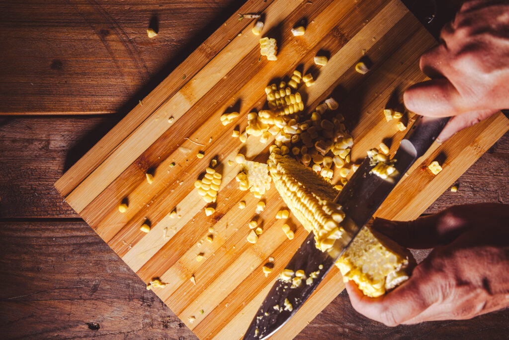 Maiskörner werden mit einem scharfen Messer vom Kolben gelöst.