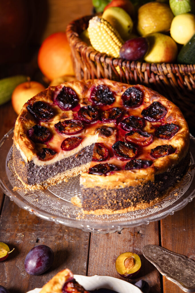 Zwetschen-Mohn-Käsekuchen, angeschnitten auf einem Kuchenteller.