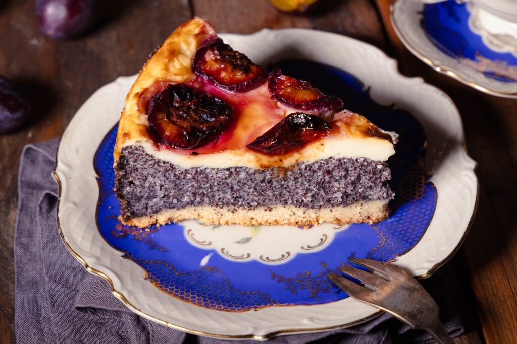 Zwetschen-Mohn-Käsekuchen, ein Stück mit Silbergabel auf einem antiken Sammelteller.