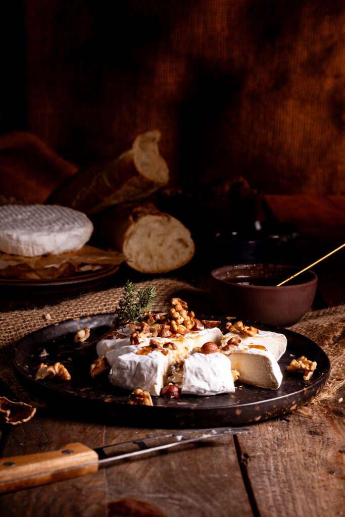 Selbstgemachter, veganer Camembert mit Nüssen auf einem Teller.