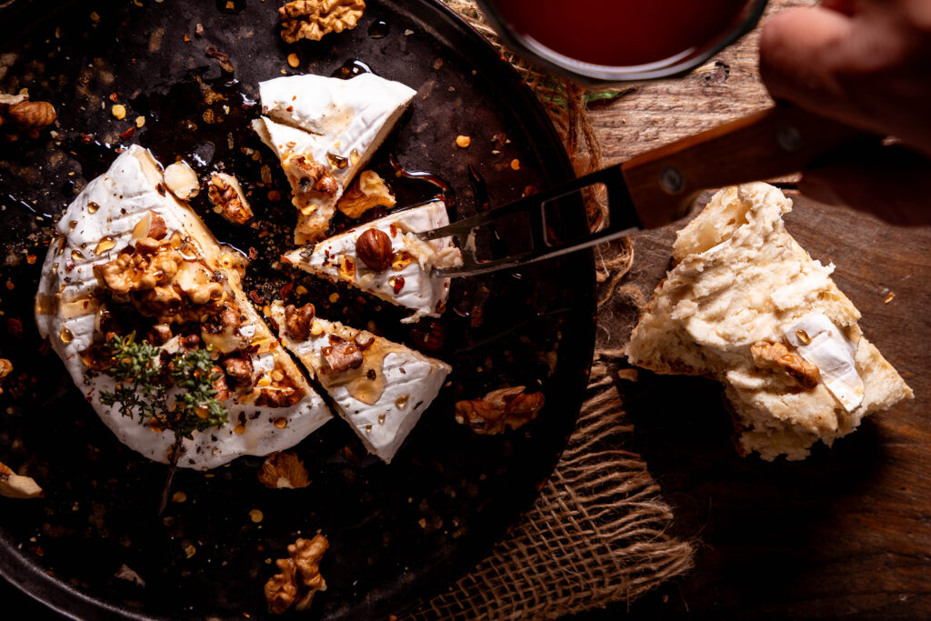Blumenbert – Veganer Camembert auf Blumenkohlbasis. Mit veganem Honig und Nüssen auf einem Teller.