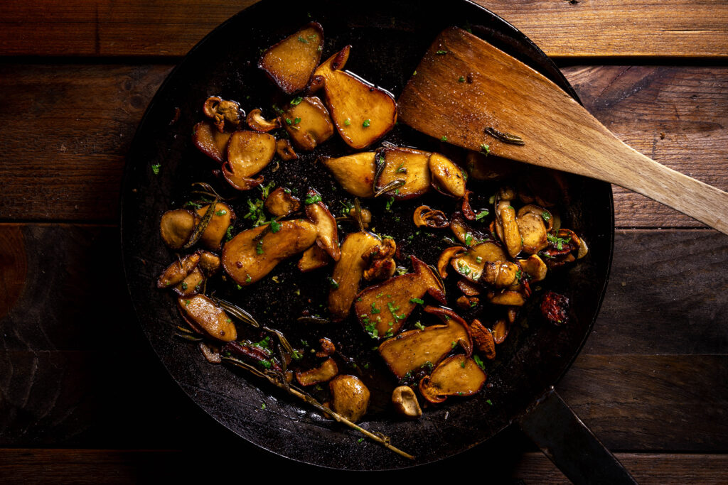 Funghi Porcini trifolati in einer gusseisernen Bratpfanne.