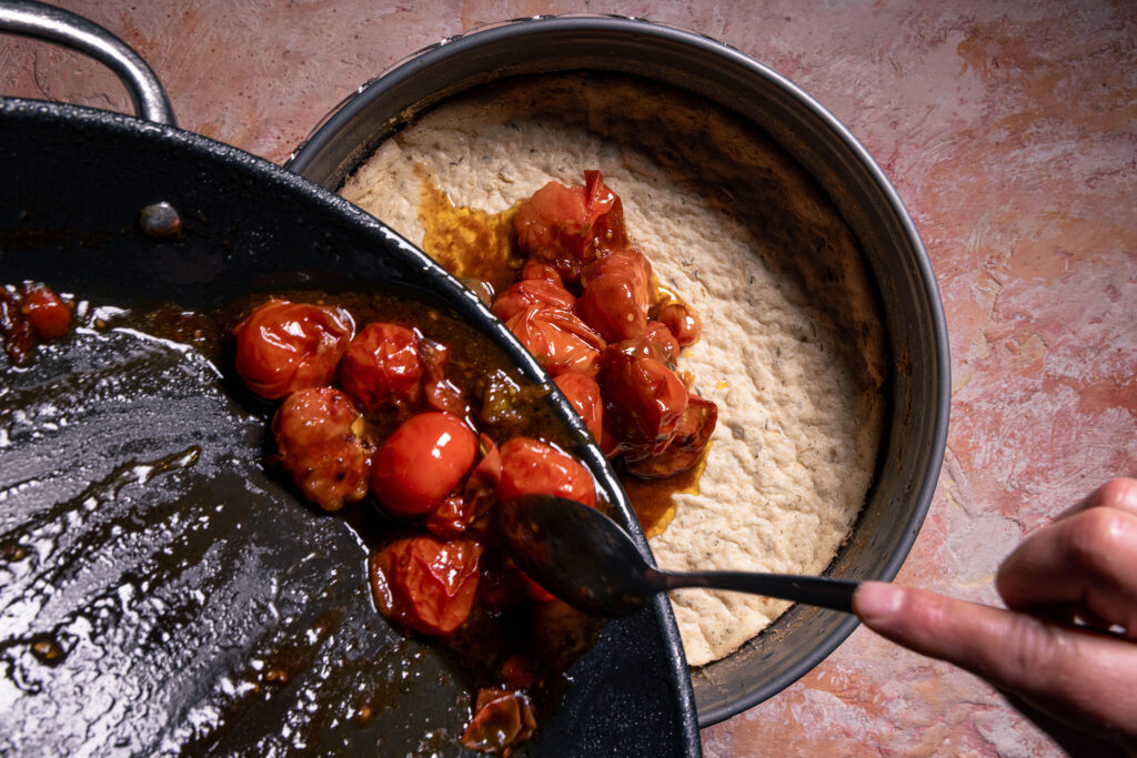 Geröstete Tomaten werde mit ihrem Sud auf den Käsekuchen gegeben.