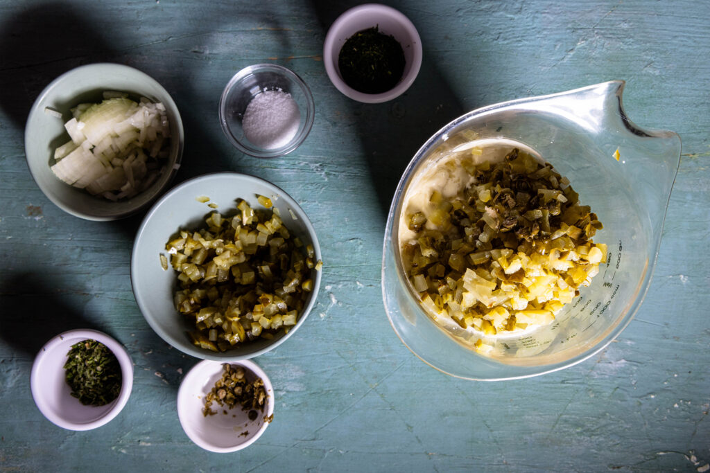 Saure Gurken, Zwiebel und Kapern werden in eine vegane Mayonnaise gegeben.