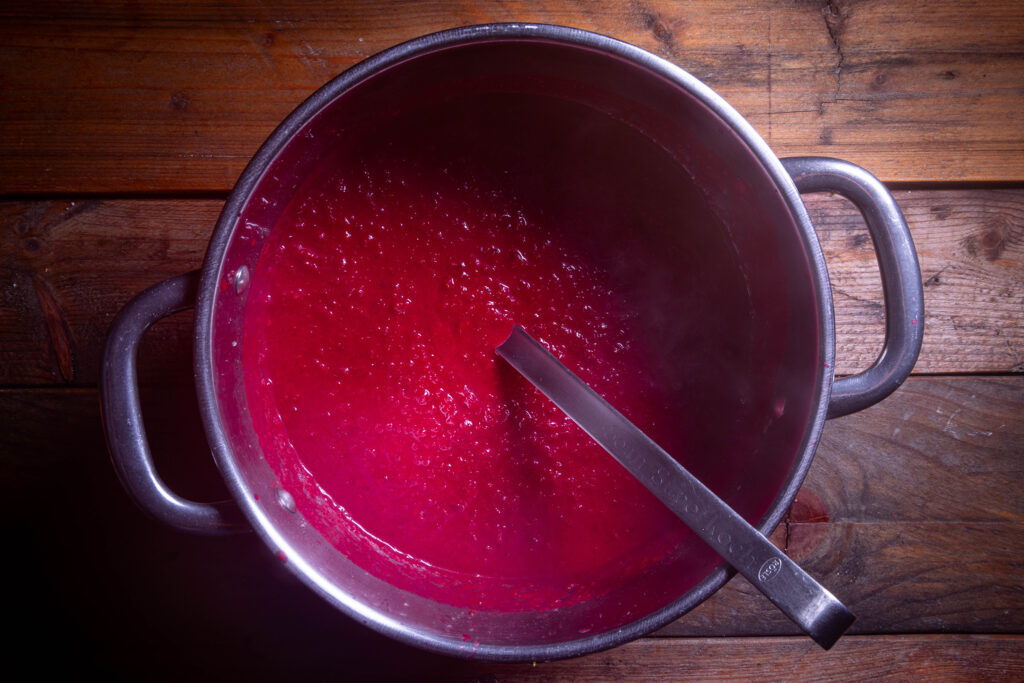 Rote-Beete-Apfel-Suppe mit einer Suppenkelle in einem Kochtopf.