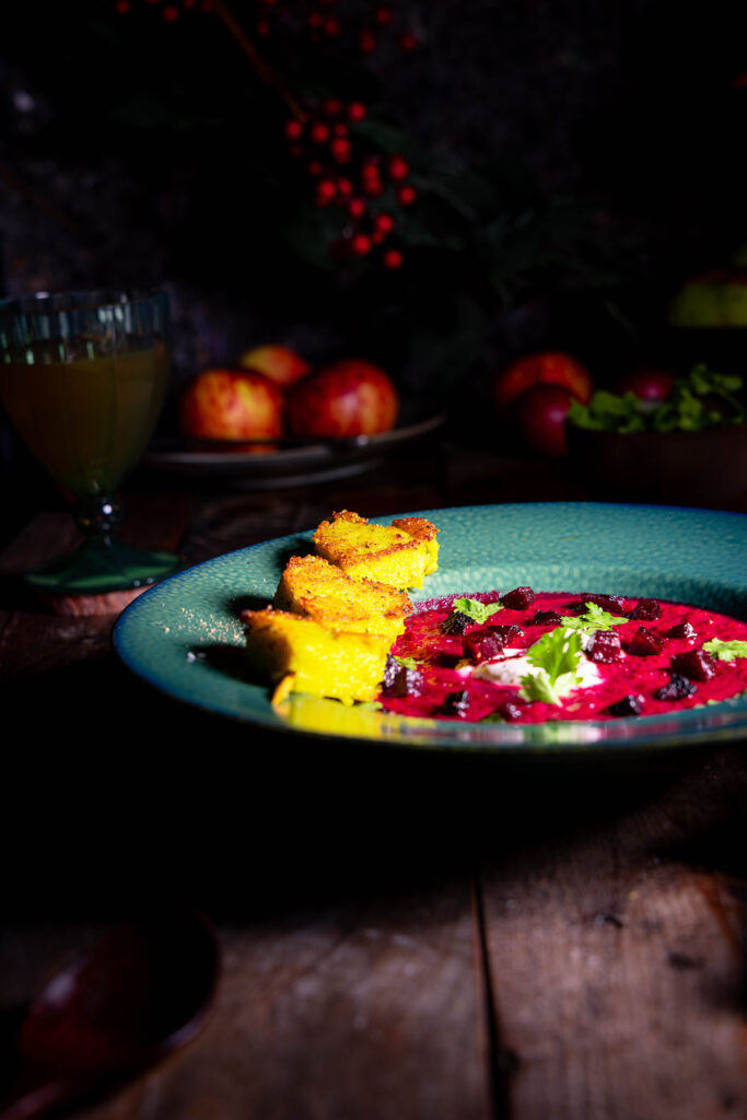 Ein grüner Teller mit Rote-Beete-Apfel-Suppe und einem Polentaspieß.