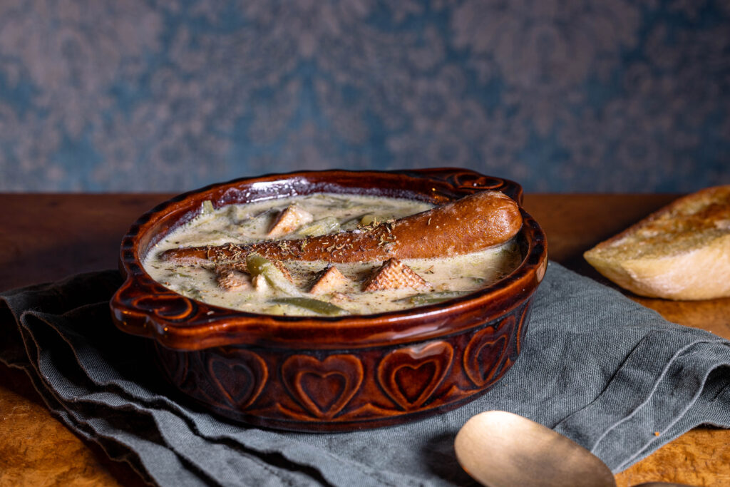 Schnippelnbohnensuppte mit einer veganen Wurst in einer Schale.
