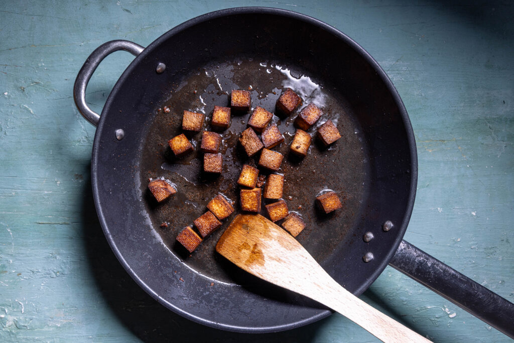 Räuchertofu brät in einer Pfanne.