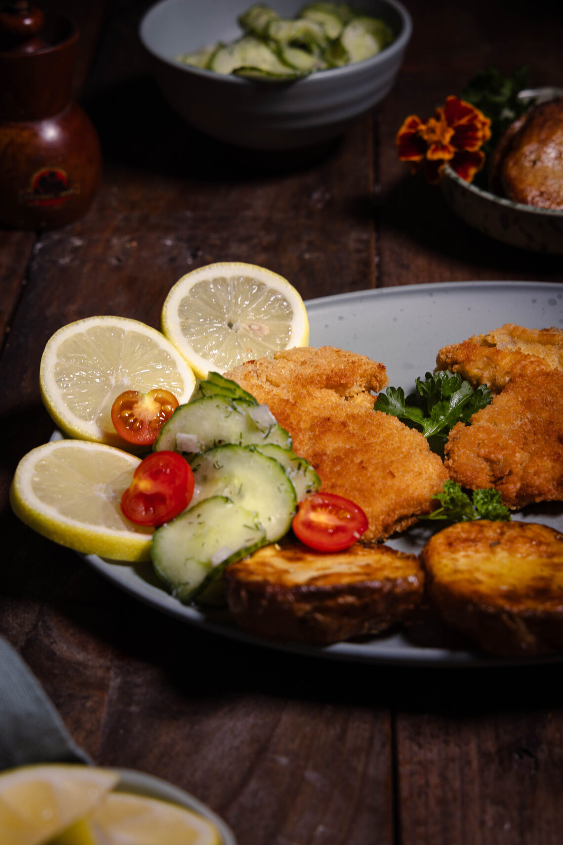Steinpilz-Schnitzel - frisch aus dem Wald und vegan, auf einem Teller mit Zitrone, Gurkensalat und gerösteten Kartoffeln.
