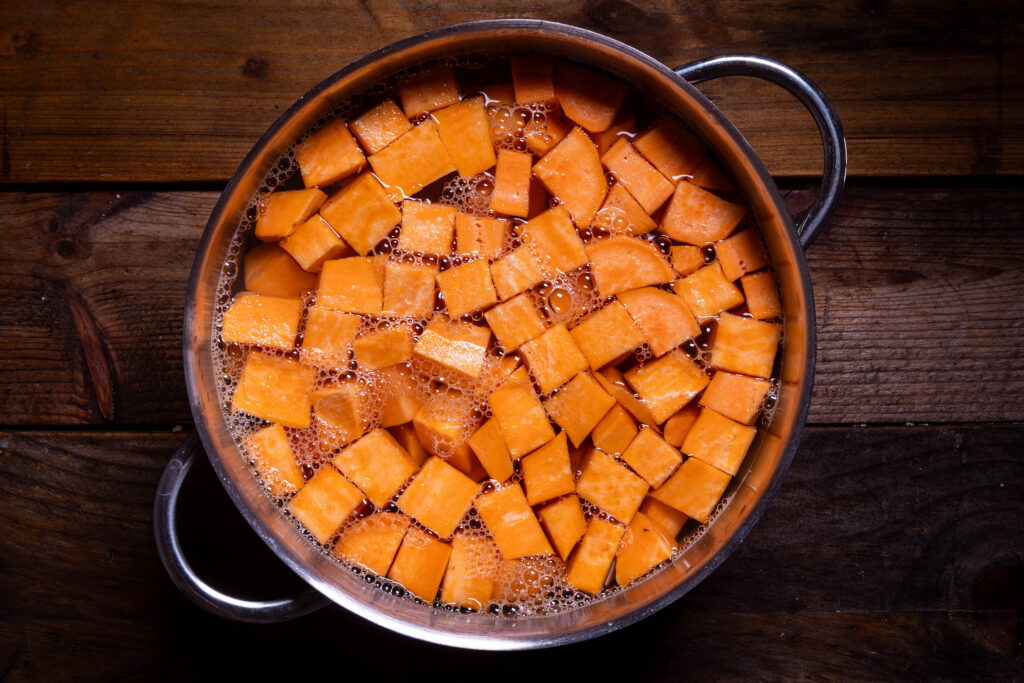 Gewürfelte Süßkartoffeln kochen in einem Kochtopf mit Salzwasser.