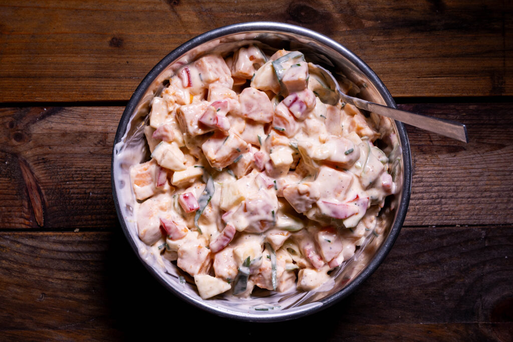 Süßkartoffelsalat wird in einer Schüssel vermengt.