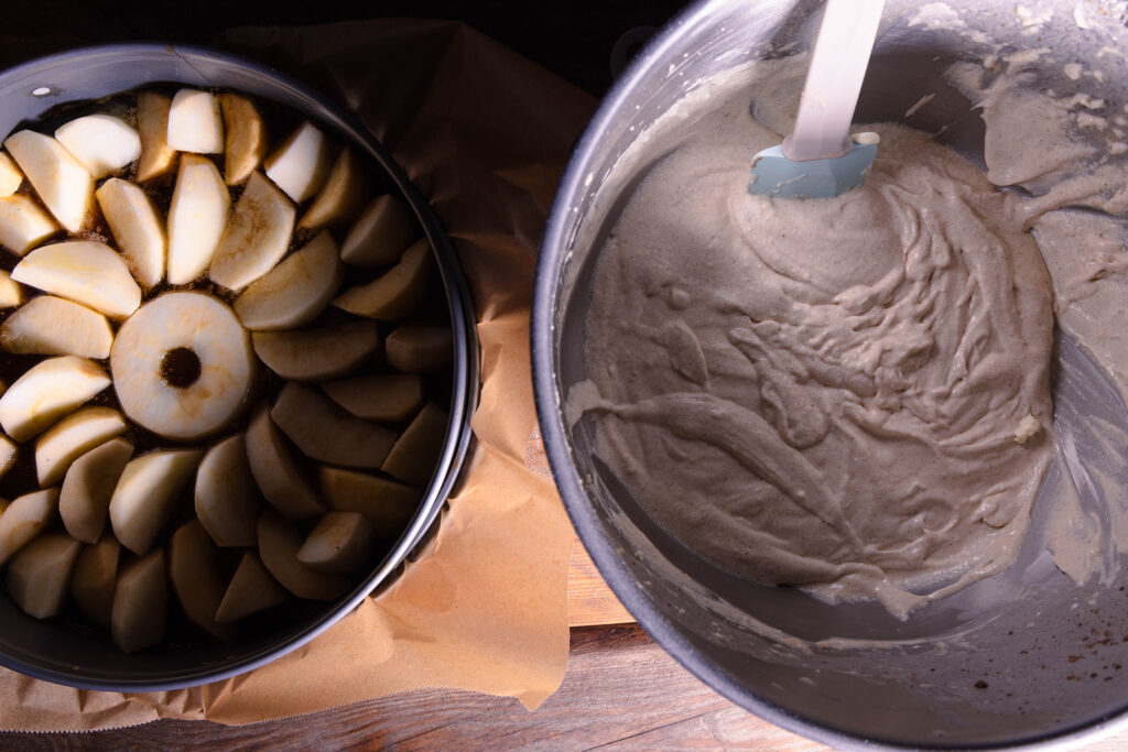 Eine Springform mit Äpfeln und Karamellsauce und eine Schüssel Rührteig.