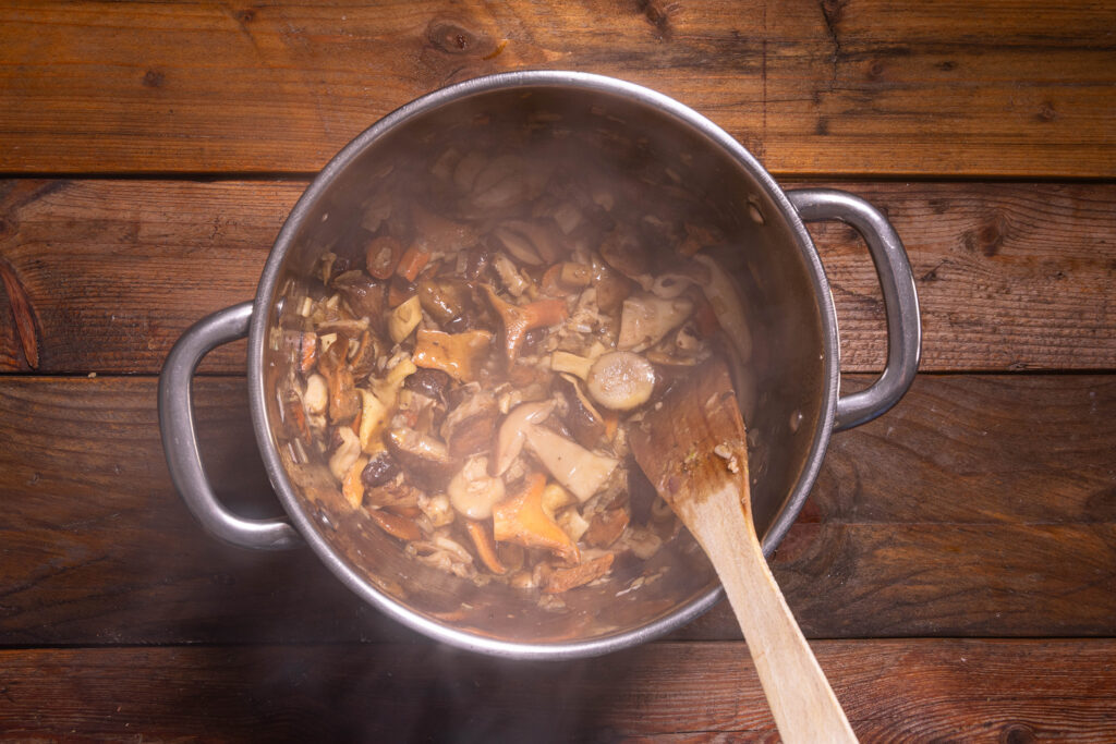 Gemischte Waldpilze braten in einem großen Topf.