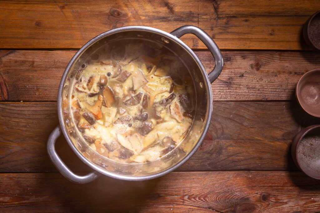 Eine Suppe aus Waldpilzen wird in einem Topf zubereitet.