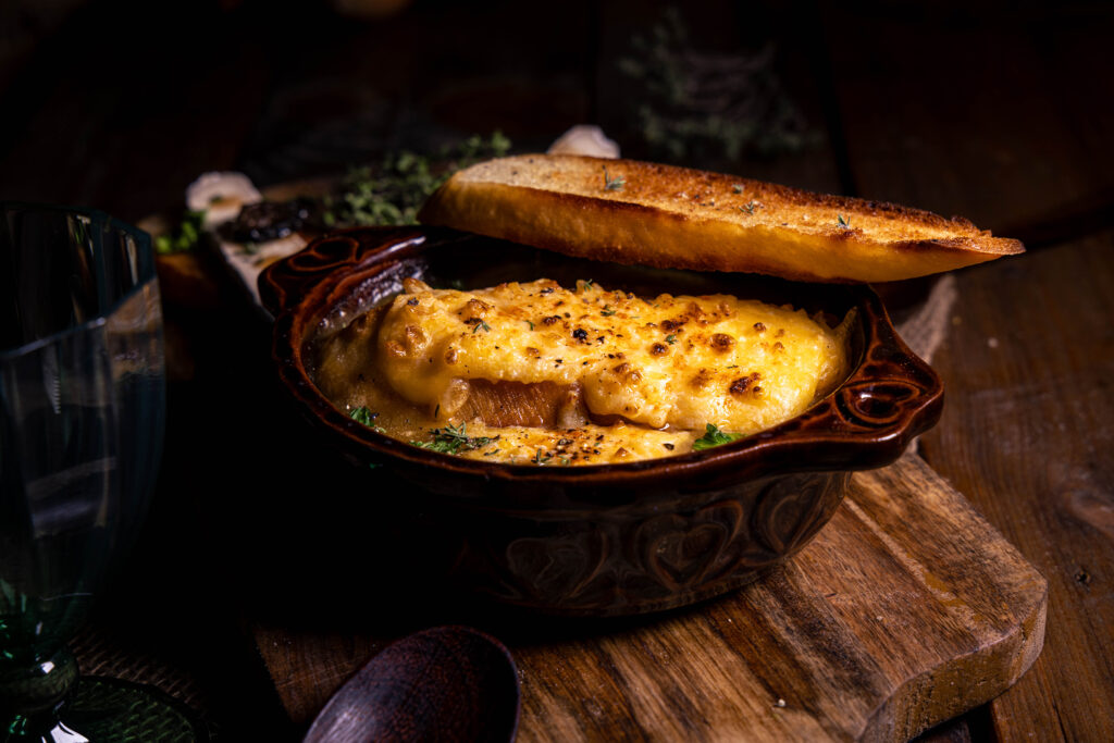 Französische Zwiebelsuppe mit extra geröstetem Brot in einer braunen, feuerfesten Schale