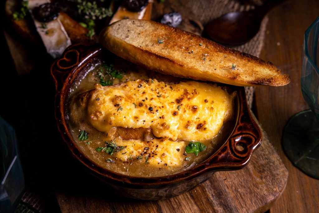 Französische Zwiebelsuppe mit extra geröstetem Brot in einer braunen, feuerfesten Schale