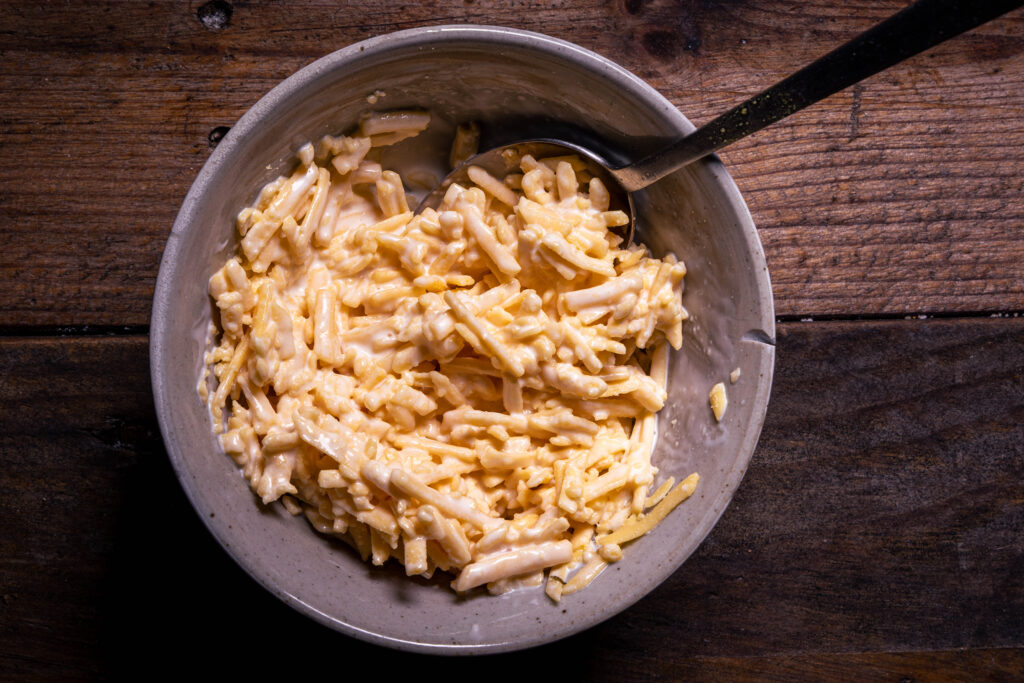 Veganer Streukäse wird in einer Schale mit veganer Sahne verrührt.