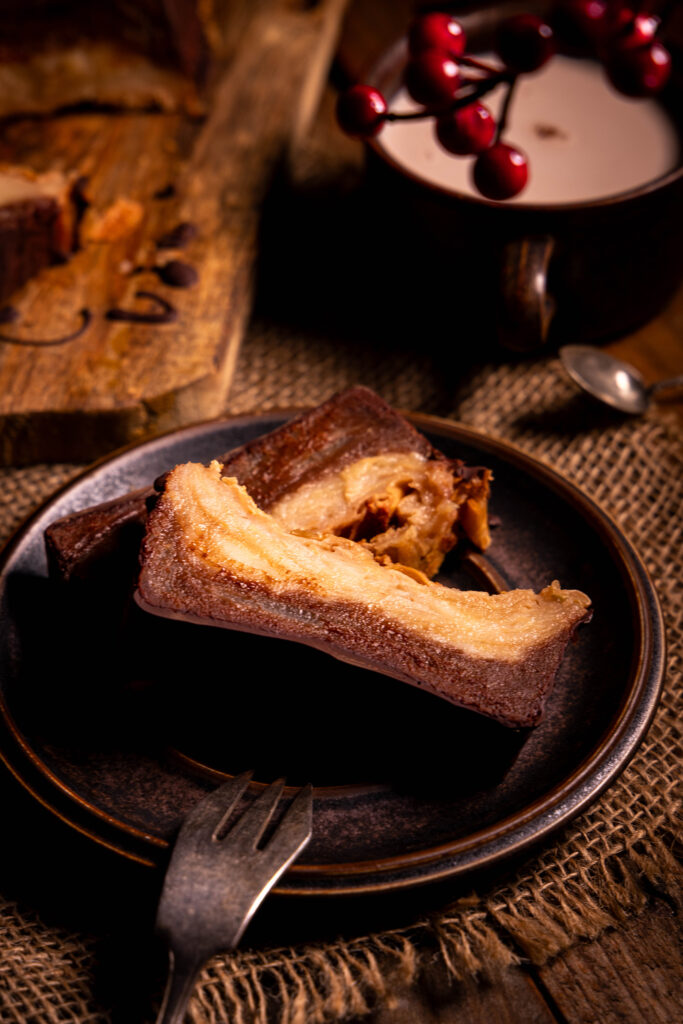 Geschichteter Apfelmarmorkuchen auf einem Teller, dahinter eine Tasse Kakao.