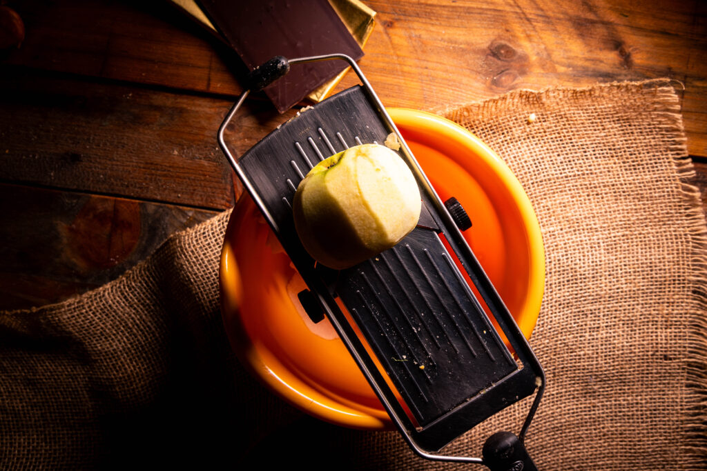 Ein Apfel wird in eine Schüssel gehobelt.