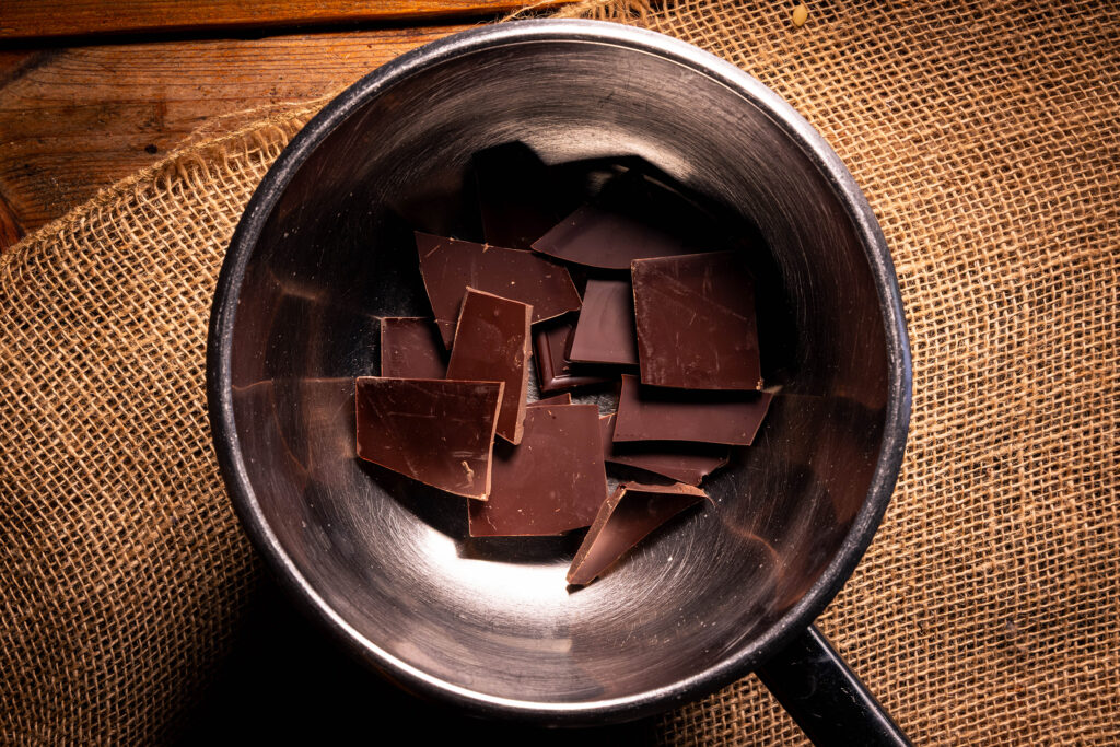 Zartbitterschokolade in einer Schüssel schmilzt über einem Wasserbad.