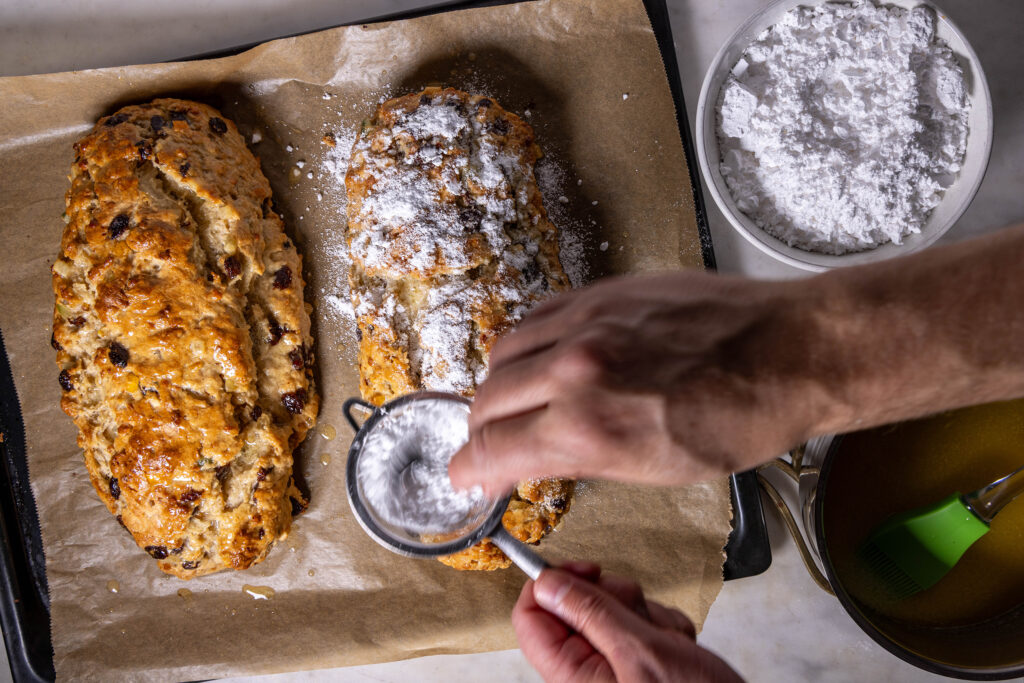 Vegane Stollen werden mit veganer Butter bestrichen und mit Puderzucker bestreut.