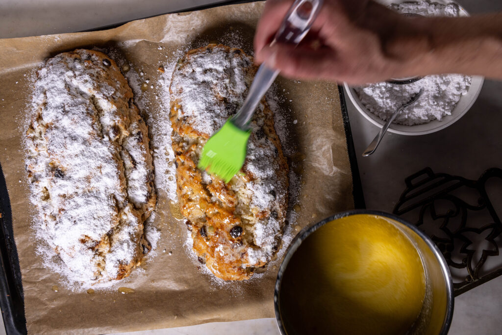 Vegane Stollen werden mit veganer Butter bestrichen und mit Puderzucker bestreut.