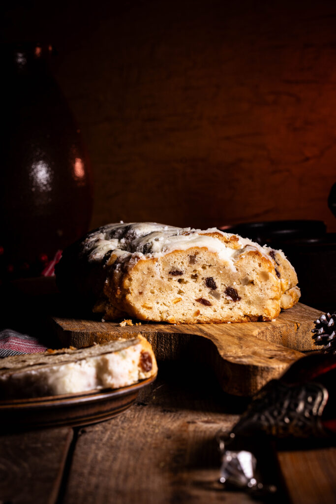 Veganer Christstollen, angeschnitten. Davor antike Weihnachtsdeko.