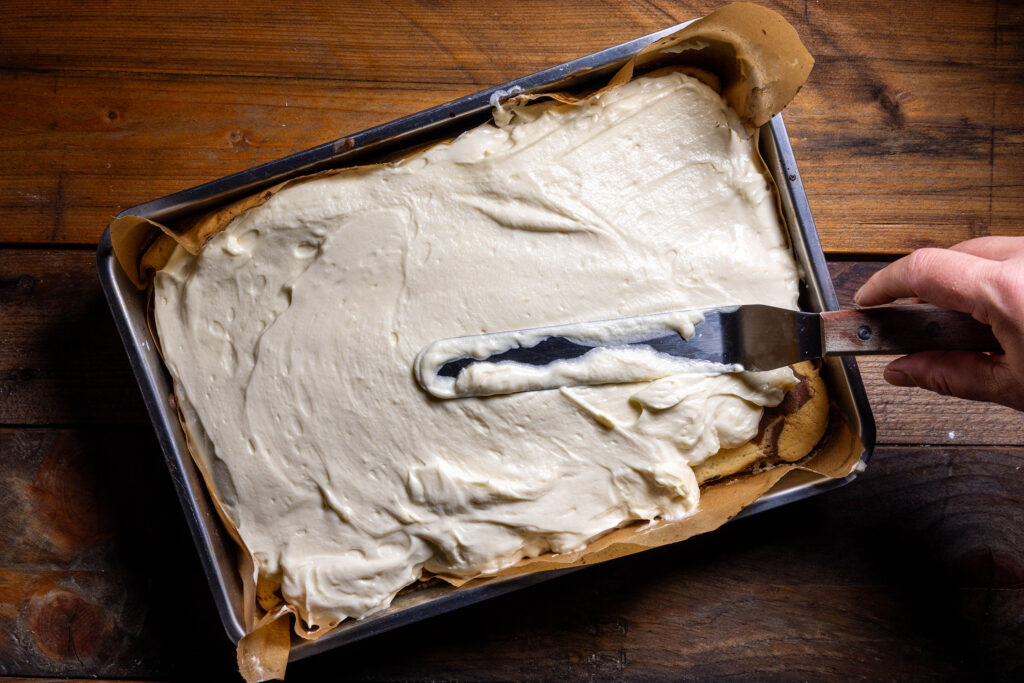 Vegane Puddingbuttercreme wird auf einem Kuchen glatt gestrichen.