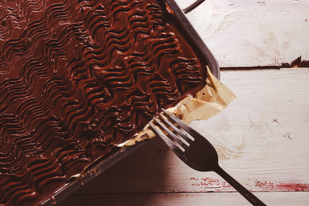 Wellen werden mit einer Gabel in eine vegane Donauwellenglasur gezeichnet.