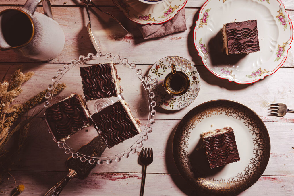 Vegane Donauwelle auf einer Etagere, auf Tellern, auf einer gedeckten Kuchentafel