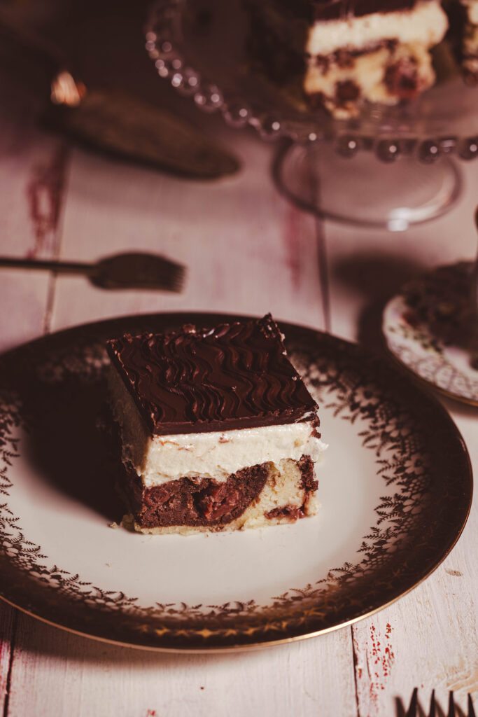 Ein Stück vegane Donauwelle auf einem antiken Kuchenteller.