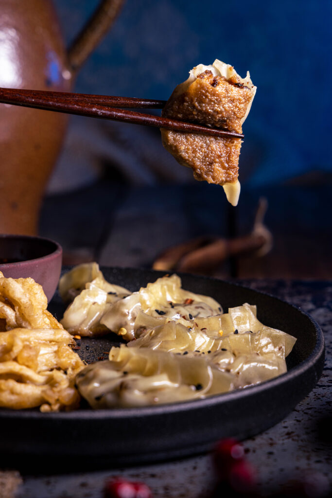 Vegane Gyoza: auf einem Teller und angebissen zischen Stäbchen.