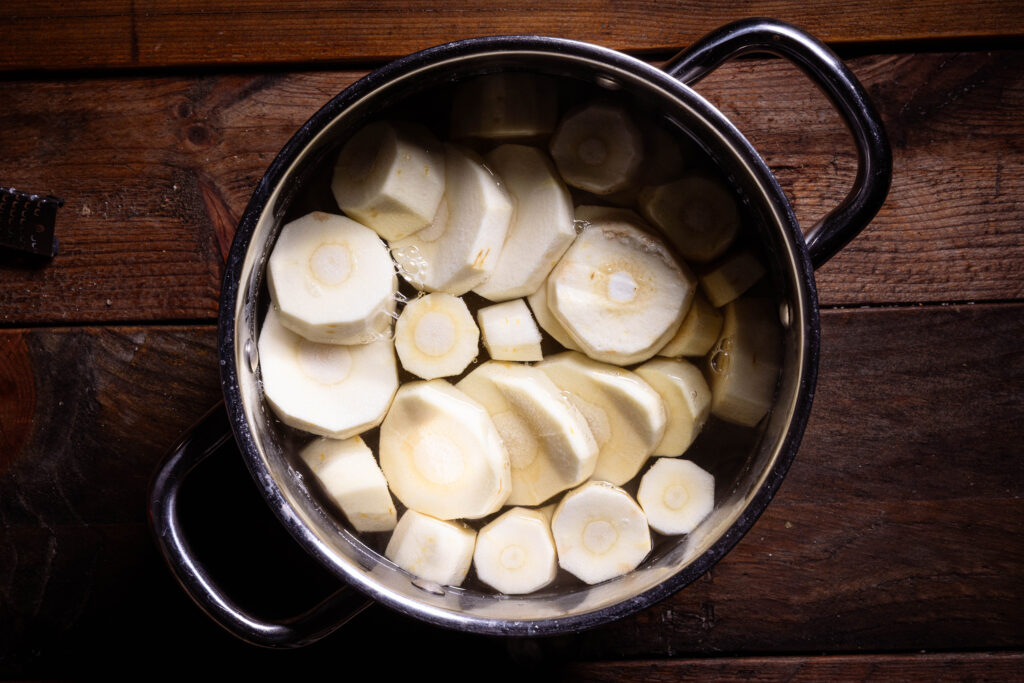 Pastinaken und Kartoffeln kochen in Salzwasser in einem Topf.